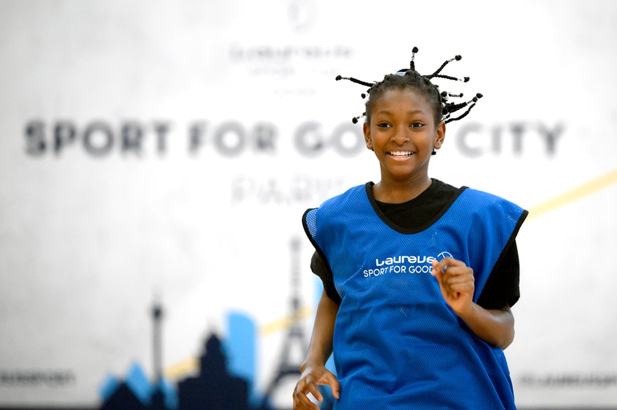 Young girl running race wearing Laureus T-shirt Sport for Good